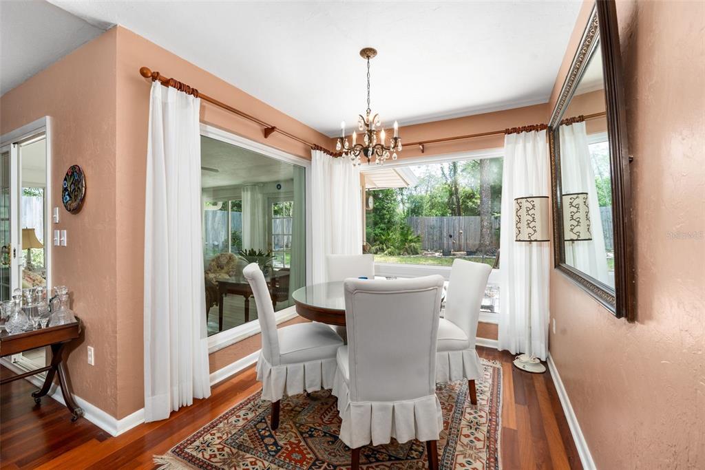 A dining room features a round table, white skirted chairs, a chandelier, and large windows — 3815 NW 48TH TERRACE, GAINESVILLE, FL