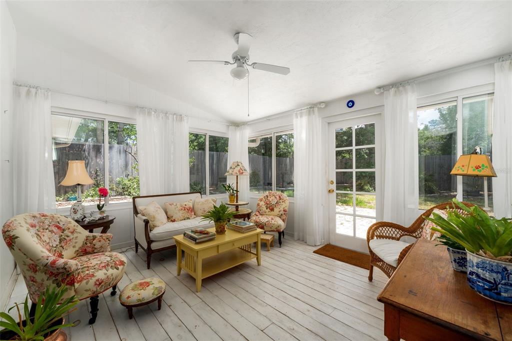 A sunroom features white wood floors, floral furniture, a ceiling fan, and large windows — 3815 NW 48TH TERRACE, GAINESVILLE, FL