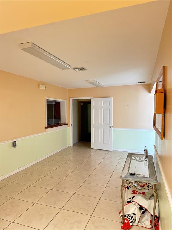 An interior room features light-colored walls with wainscoting, tile flooring, and a glass-topped console table — 706 N 7TH STREET, FORT PIERCE, FL
