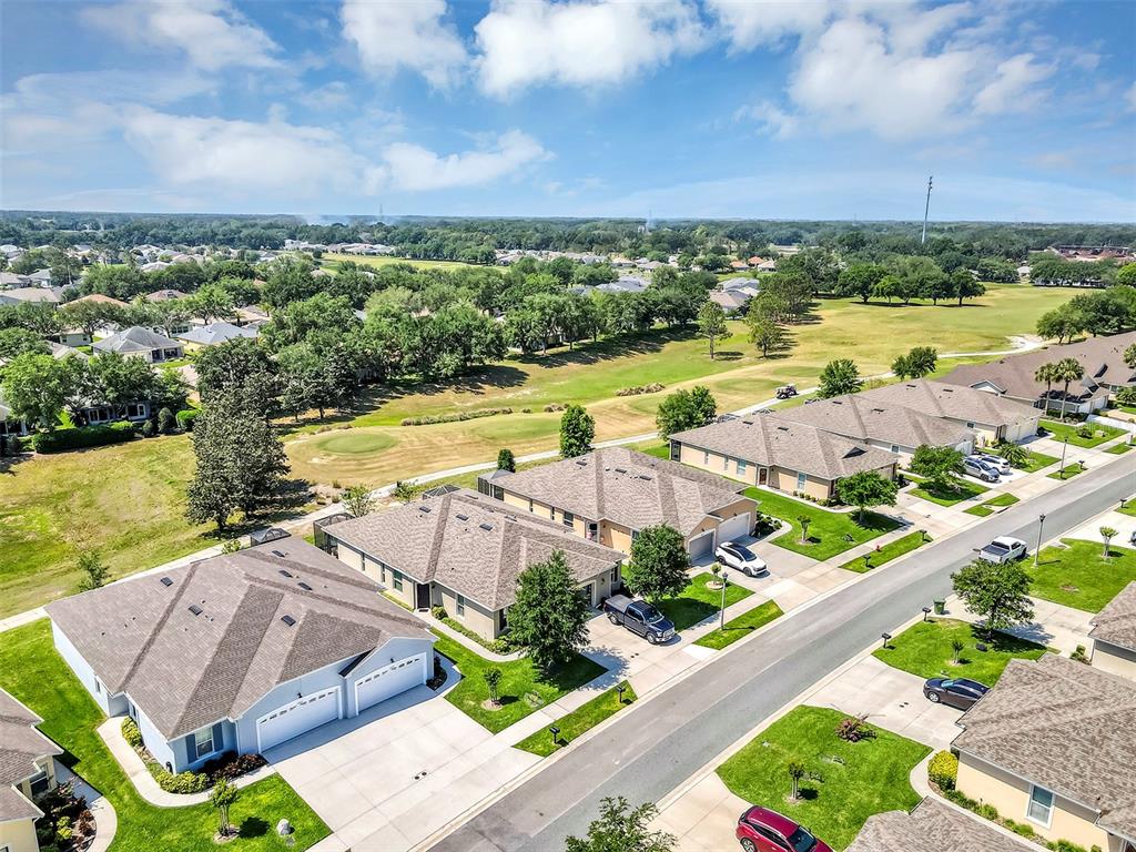 An aerial view shows several suburban houses with shingled roofs bordering a golf course — 27018 WHITE PLAINS WAY, LEESBURG, FL
