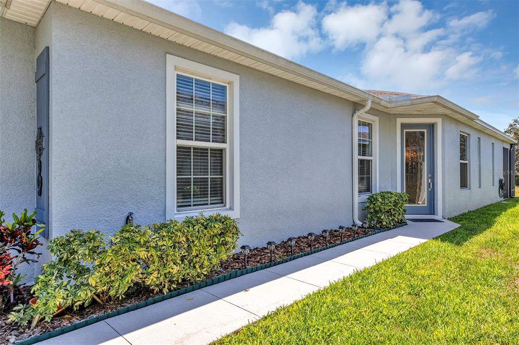 A light blue stucco house exterior features a walkway, landscaping, and a glass-paneled door — 27018 WHITE PLAINS WAY, LEESBURG, FL