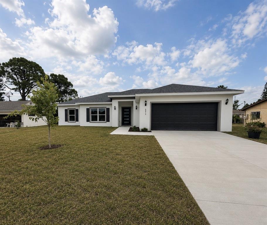 An open-concept living and dining area features a modern kitchen, wood-toned cabinetry, and tile flooring — 5813 REGENT ROAD, VENICE, FL