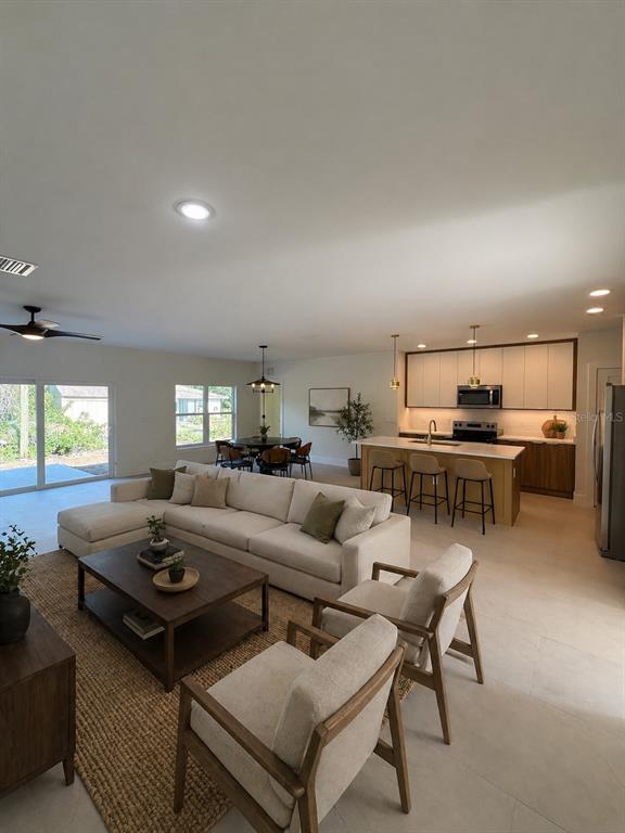A living room features a ceiling fan, a television on a console, and neutral furniture — 5813 REGENT ROAD, VENICE, FL