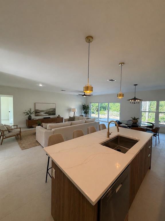An open-concept living room and kitchen feature neutral tones, a large sofa, and tile flooring — 5813 REGENT ROAD, VENICE, FL