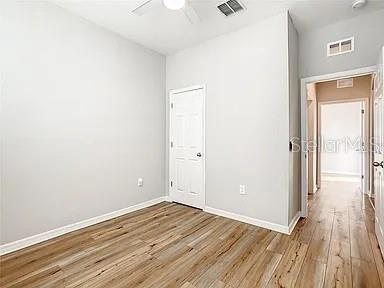 An empty room with light wood-look flooring and a white door leading to a hallway — 210 BLACKSTONE CREEK ROAD, GROVELAND, FL