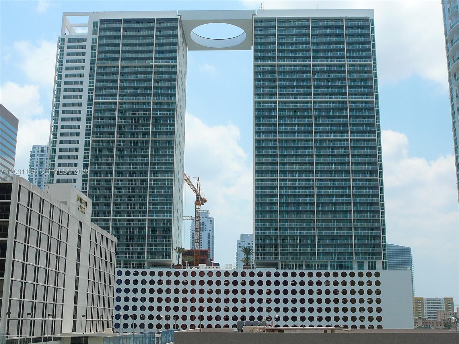 A large residential building features two towers connected by a bridge with a circular opening — 500 Brickell Ave # 1808, Miami FL 33131, MIAMI, FL