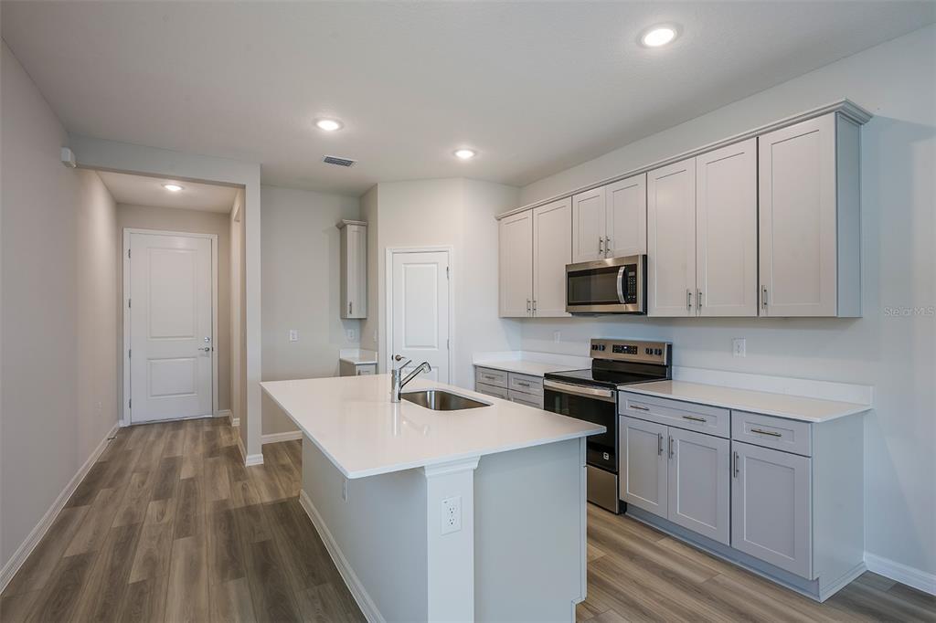 A kitchen with light gray cabinets, a white quartz island, and wood-look flooring — 6125 SW 96TH PLACE, OCALA, FL