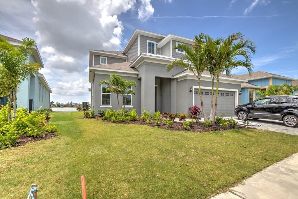 A two-story gray house with a two-car garage and a view of a lake — 5327 WISHING ARCH DRIVE, APOLLO BEACH, FL
