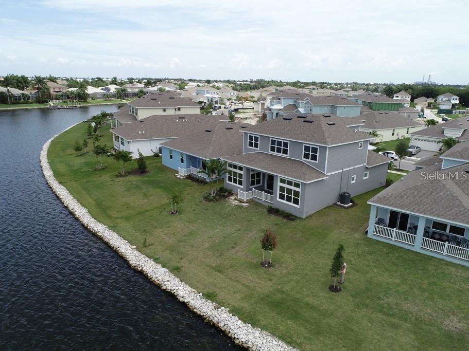 An aerial view shows several suburban houses situated along a curved waterfront with rock edging — 5327 WISHING ARCH DRIVE, APOLLO BEACH, FL