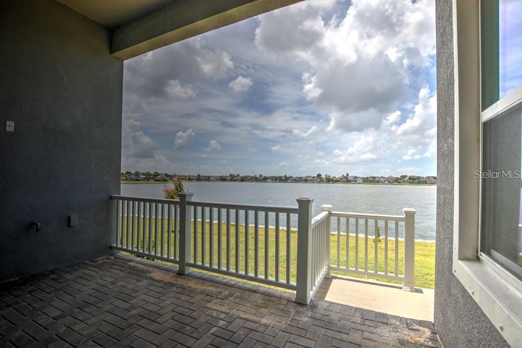 A covered patio with brick pavers overlooks a lake and a grassy yard — 5327 WISHING ARCH DRIVE, APOLLO BEACH, FL