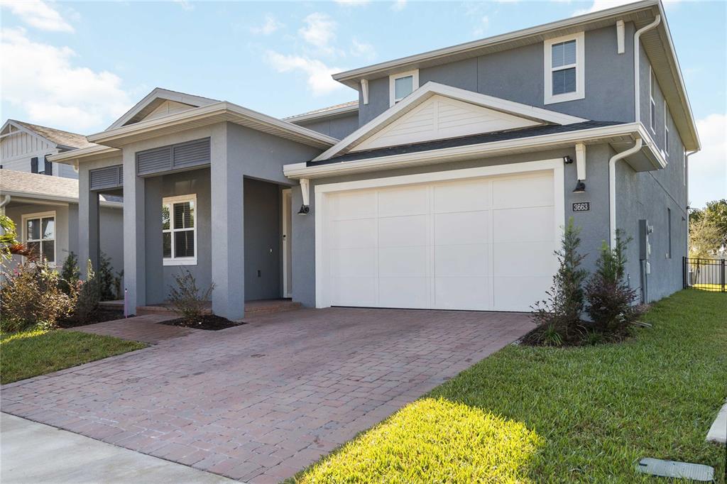 A two-story house with a gray stucco exterior, a white garage door, and brick driveway — 3663 ARBORDALE LOOP, SANFORD, FL