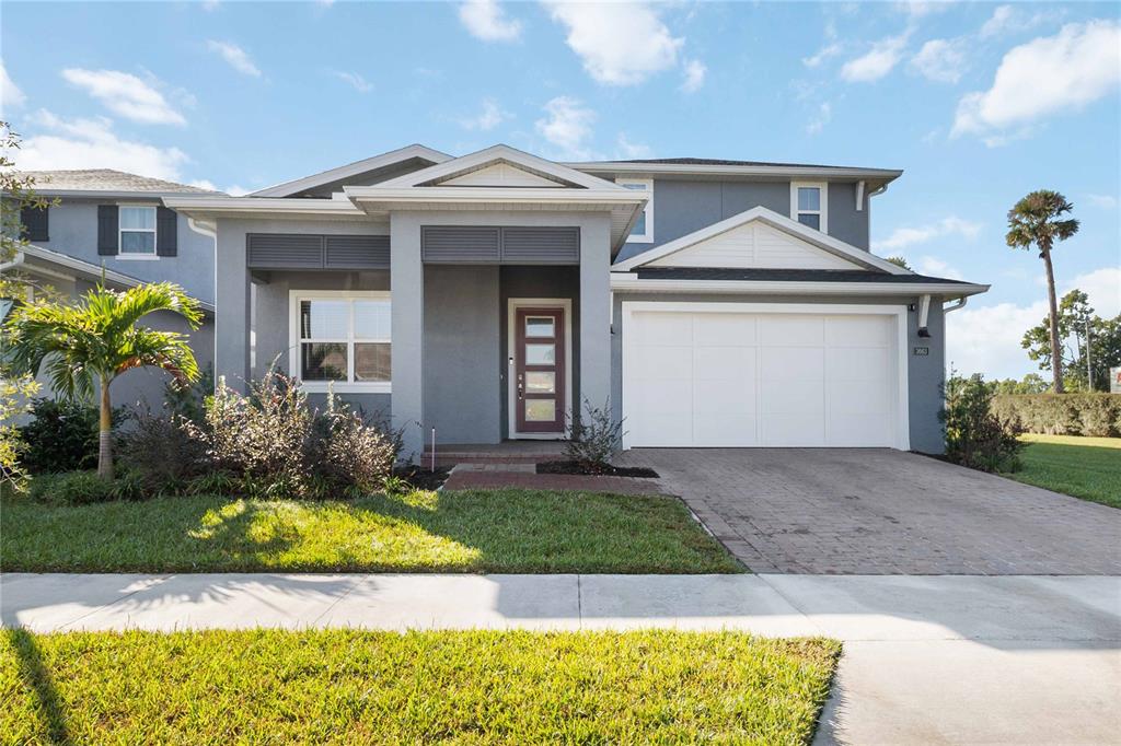 The exterior of a gray two-story suburban house with a white garage and front door — 3663 ARBORDALE LOOP, SANFORD, FL