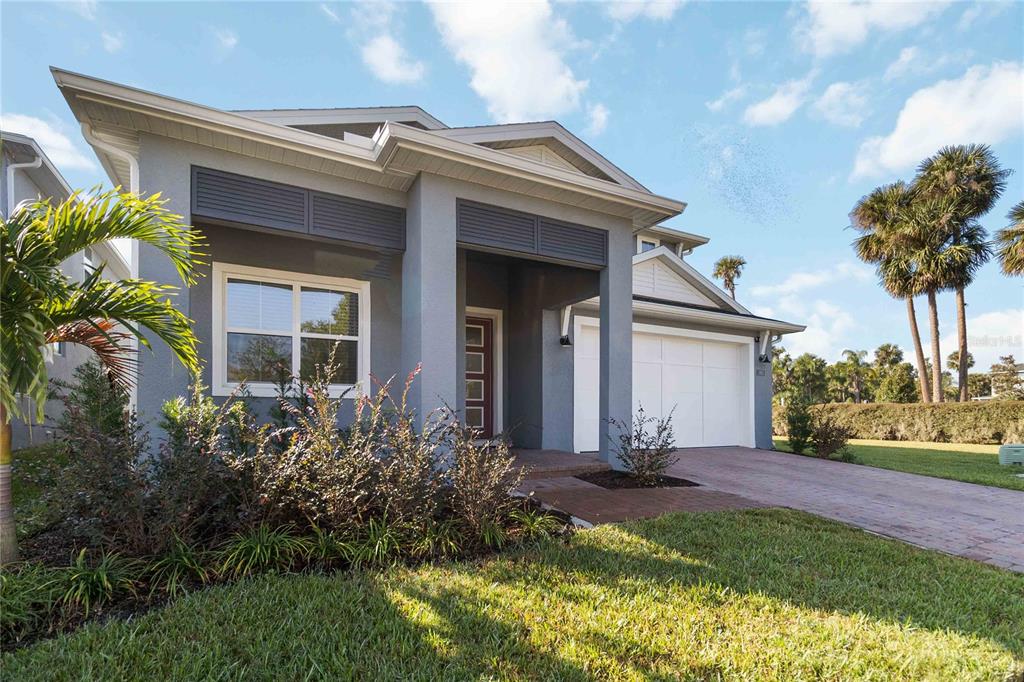 A gray single-story house with a white garage, a front porch, and a brick driveway — 3663 ARBORDALE LOOP, SANFORD, FL