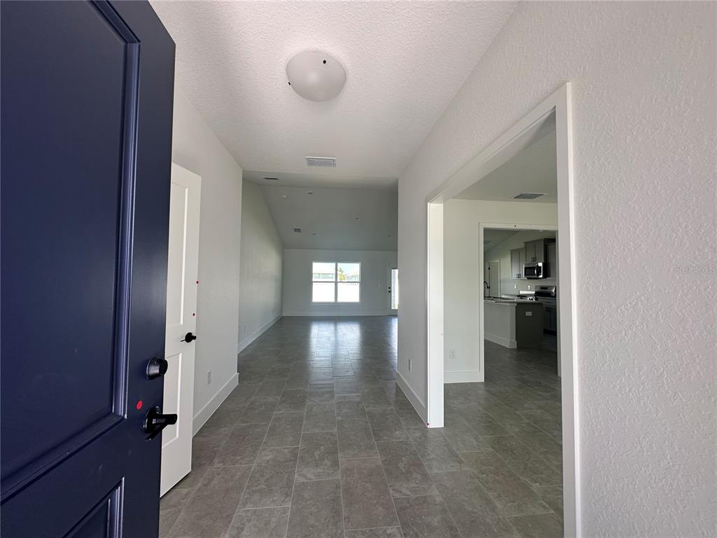 A view from an open front door into a hallway with gray tile flooring — 12605 NE 48TH STREET, OXFORD, FL