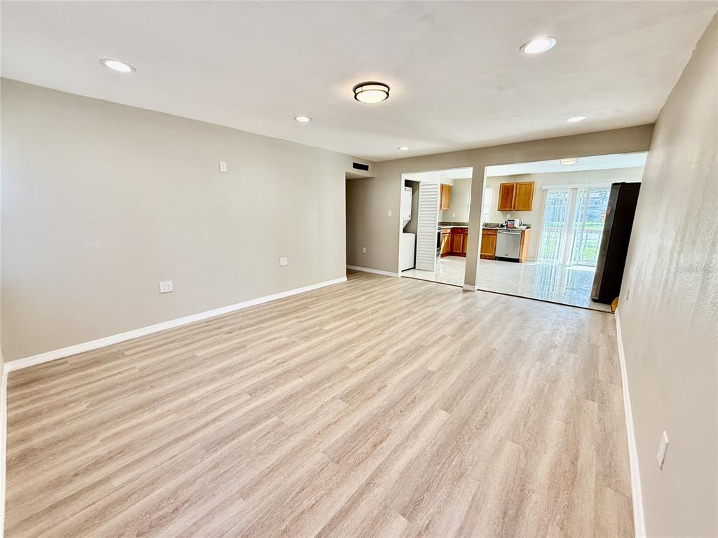 A spacious living room with light wood-look flooring leads into an open kitchen and dining area — 2769 L B MCLEOD ROAD UNIT 2769A, ORLANDO, FL