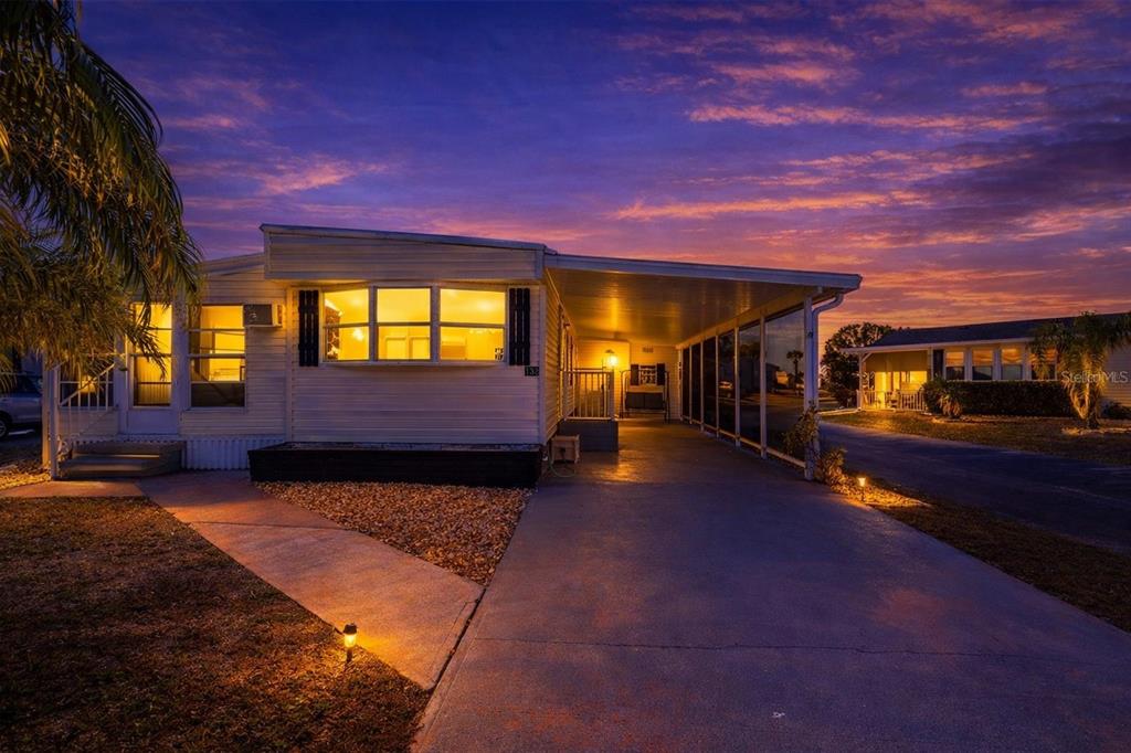 A mobile home with a carport and a gravel front yard at sunset — 1000 KINGS HIGHWAY UNIT 132, PORT CHARLOTTE, FL