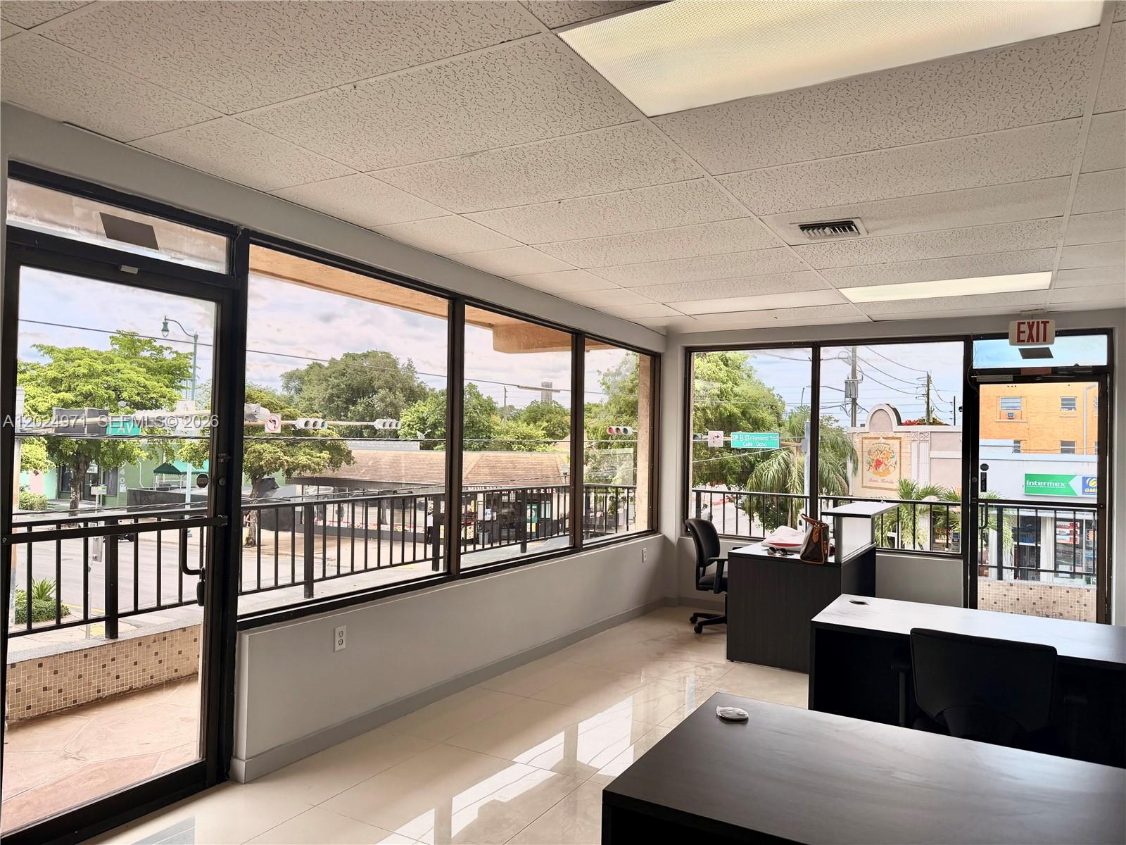 An office space features large windows, tile flooring, and a view of a city street — 1101 SW 8th St # 203, Miami FL 33130, MIAMI, FL