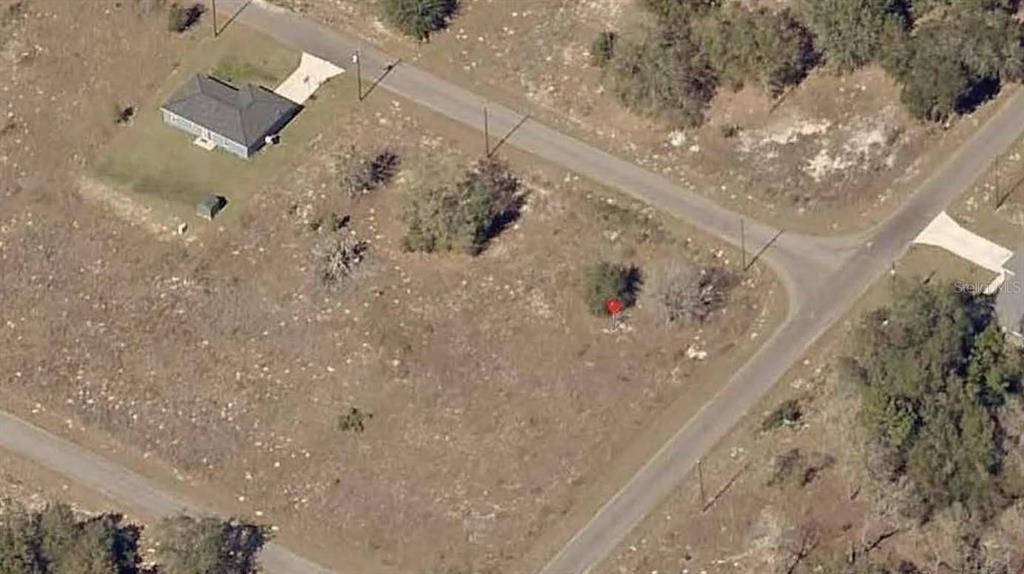 An aerial view shows a vacant, grassy corner lot with a red marker — 00 GUAVA TRACK TRAIL, OCKLAWAHA, FL