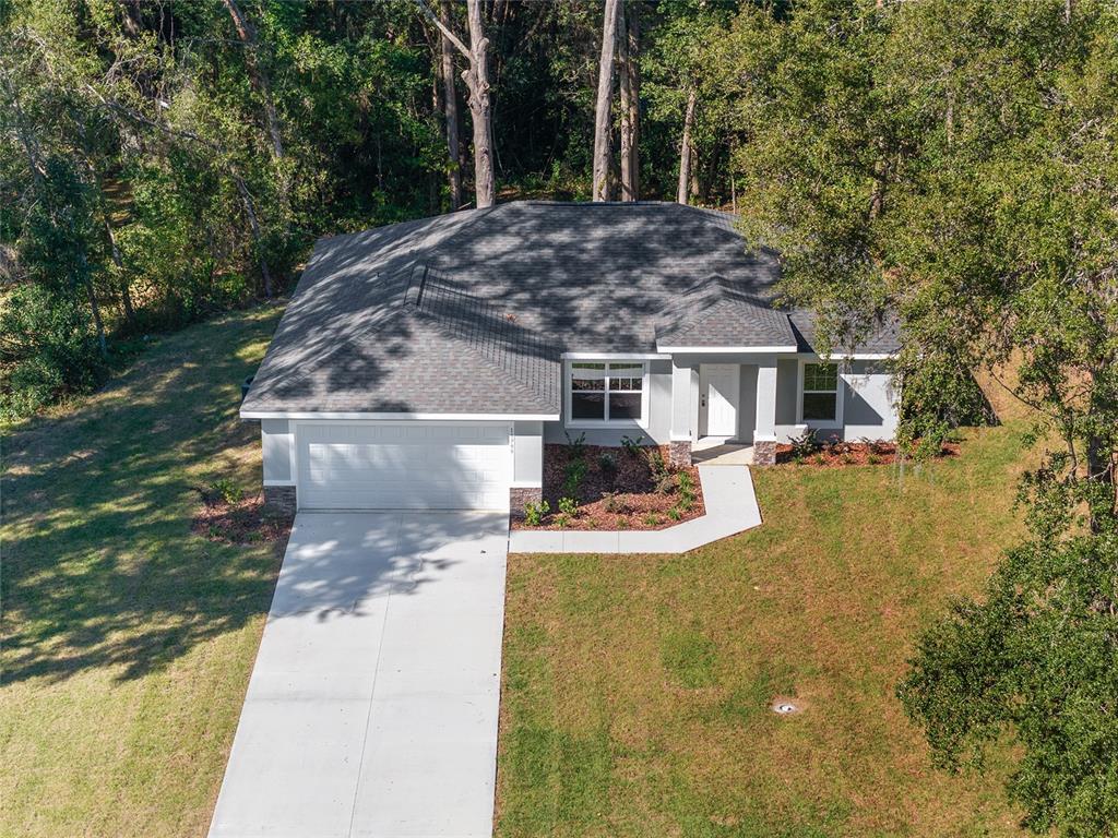 An aerial view of a single-story house with a gray roof, white garage, and landscaping — 9776 SW 196TH CIRCLE, DUNNELLON, FL
