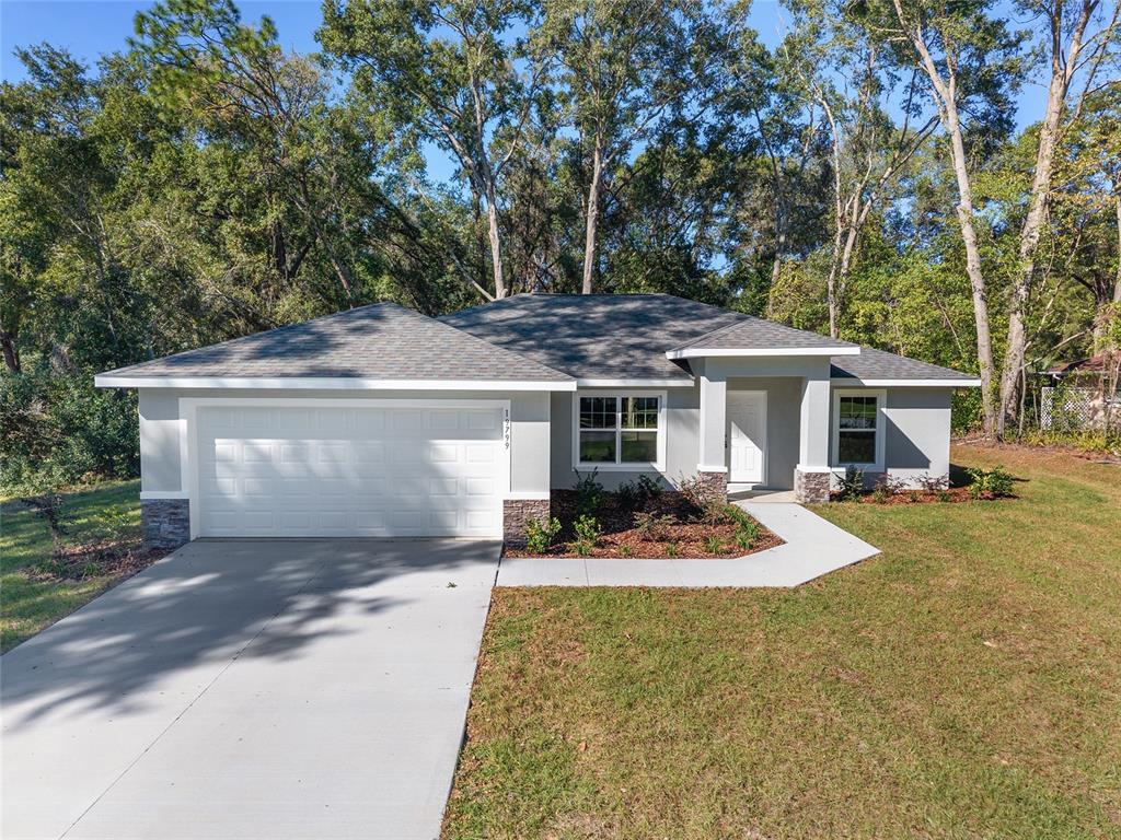 A single-story house with a gray exterior, stone accents, and a two-car garage — 9776 SW 196TH CIRCLE, DUNNELLON, FL