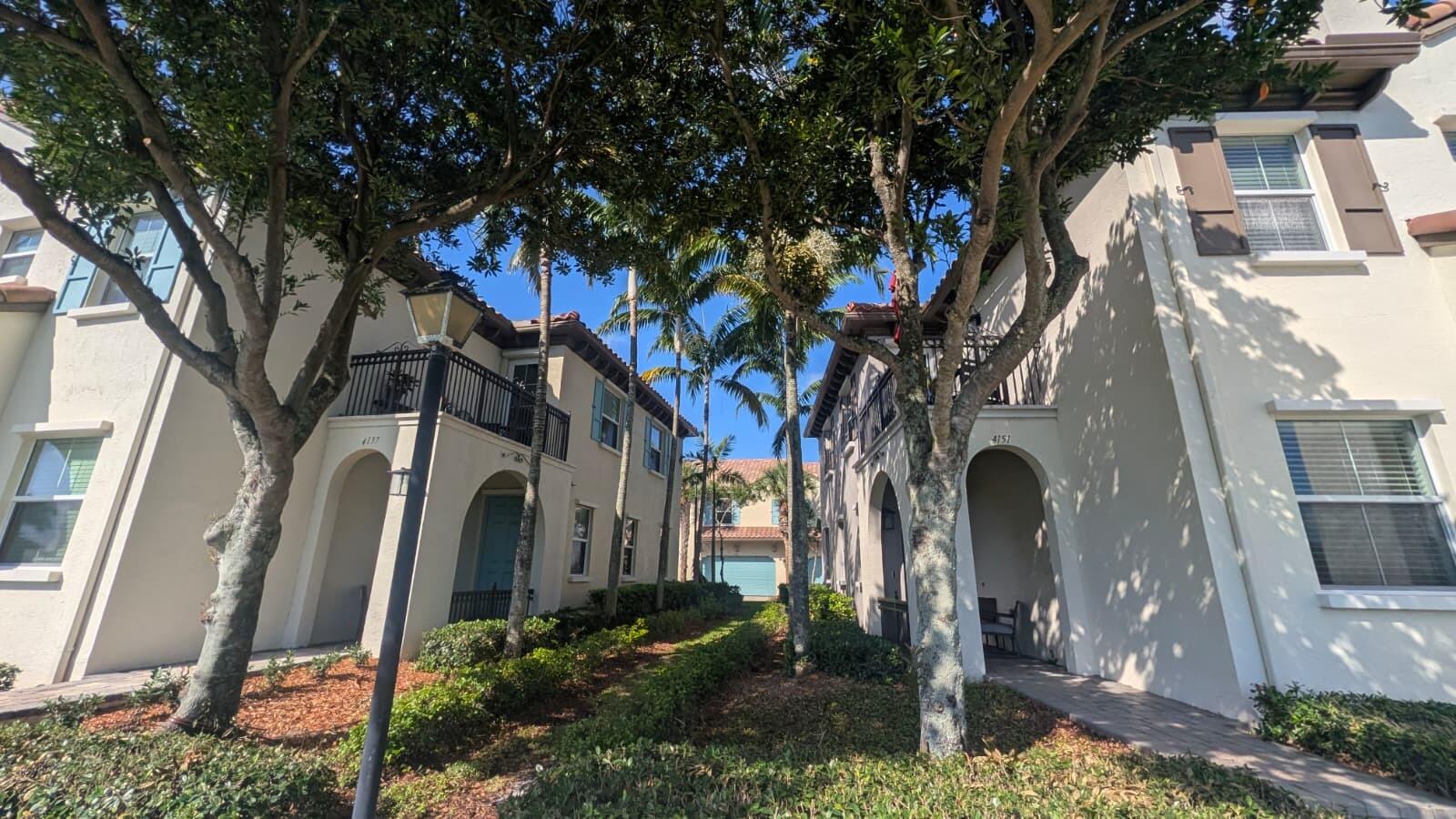 Two beige multi-story townhomes with arched entryways and balconies are separated by a landscaped walkway — 4153 Cascada Circle, Cooper City FL 33024, COOPER CITY, FL