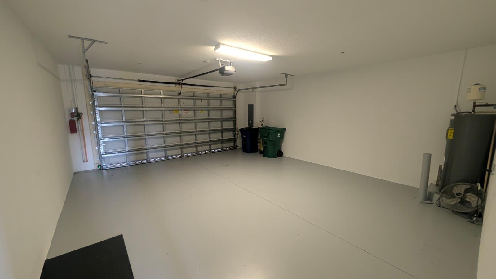 A clean, empty garage with a gray epoxy floor, white walls, and a metal door — 4153 Cascada Circle, Cooper City FL 33024, COOPER CITY, FL