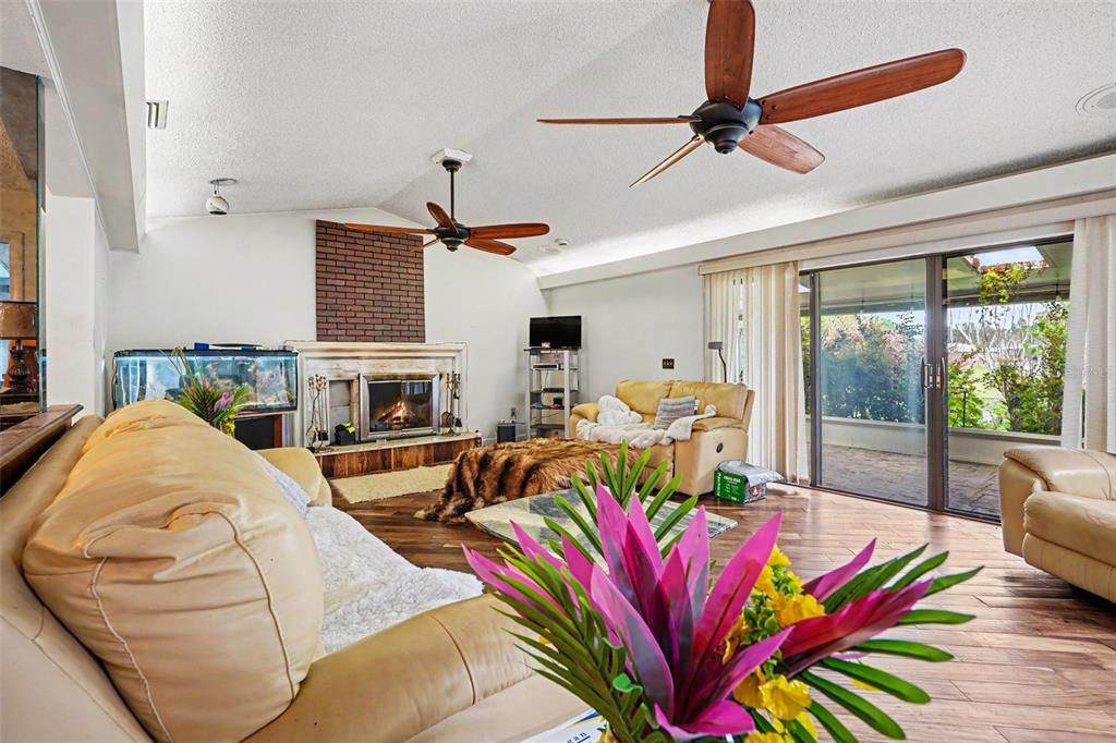 A living room with wood-look tile flooring, a ceiling fan, and sliding doors to a pool — 6141 PALMETTO DRIVE, INDIAN LAKE ESTATES, FL