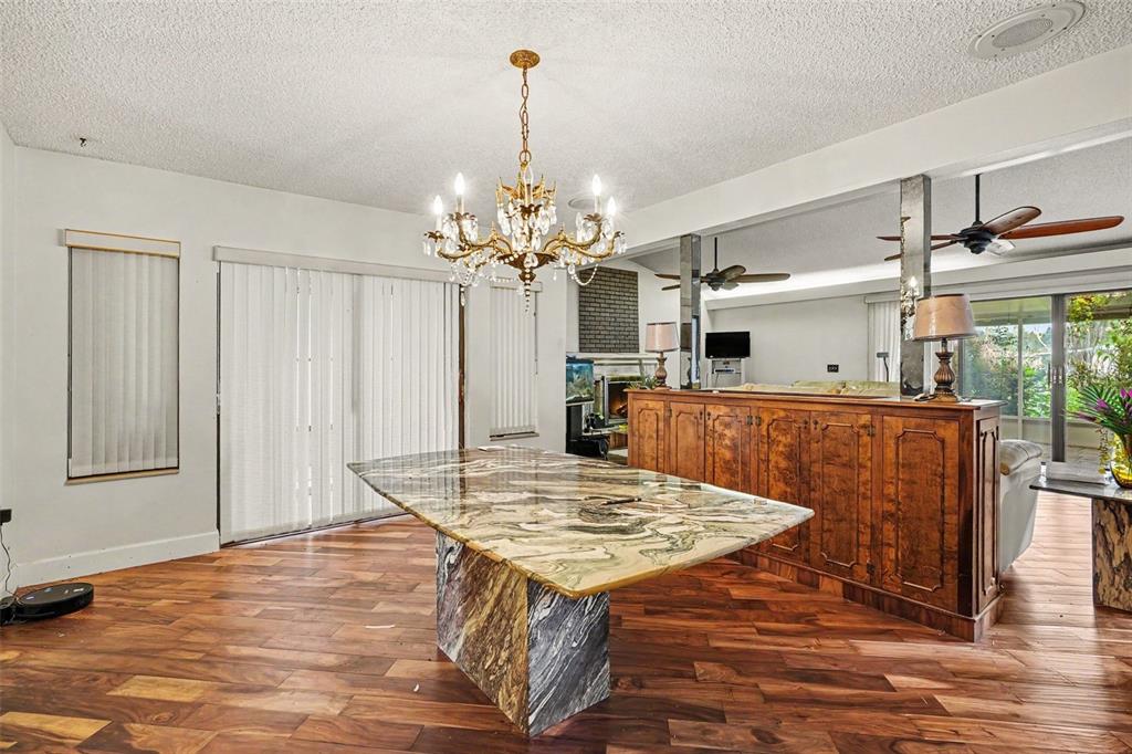 A dining area features a marble-topped table, a crystal chandelier, and dark wood flooring — 6141 PALMETTO DRIVE, INDIAN LAKE ESTATES, FL