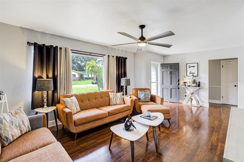 A living room features a brown sofa, two armchairs, nested coffee tables, and hardwood floors — 1636 LEISURE DRIVE, CLEARWATER, FL
