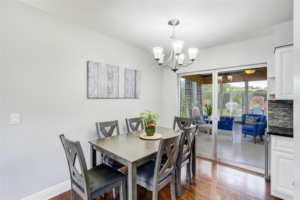 A dining room with a wooden table, six chairs, a chandelier, and a sliding glass door — 1636 LEISURE DRIVE, CLEARWATER, FL
