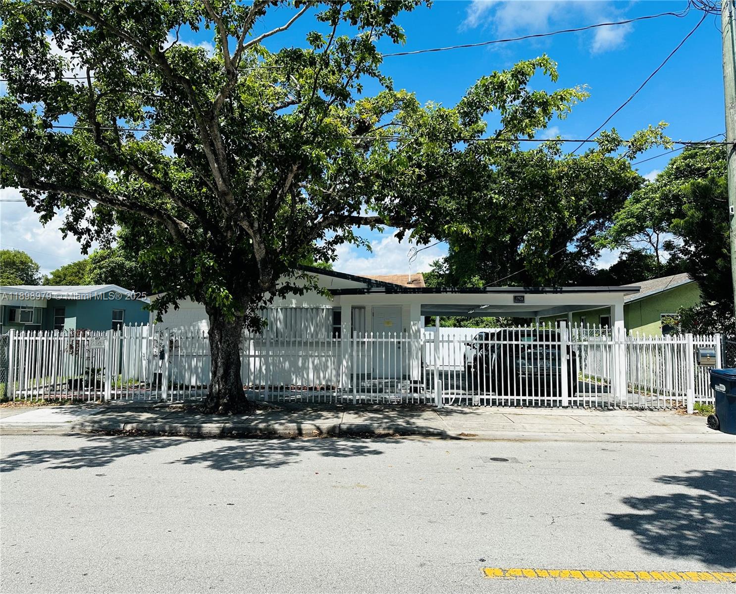 A white single-story house with a carport is enclosed by a tall white metal fence — 17926 SW 104th Ave, Miami FL 33157, MIAMI, FL