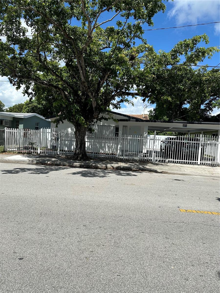 A white single-story house with a carport and a metal fence sits behind a tree — 17926 SW 104th Ave, Miami FL 33157, MIAMI, FL