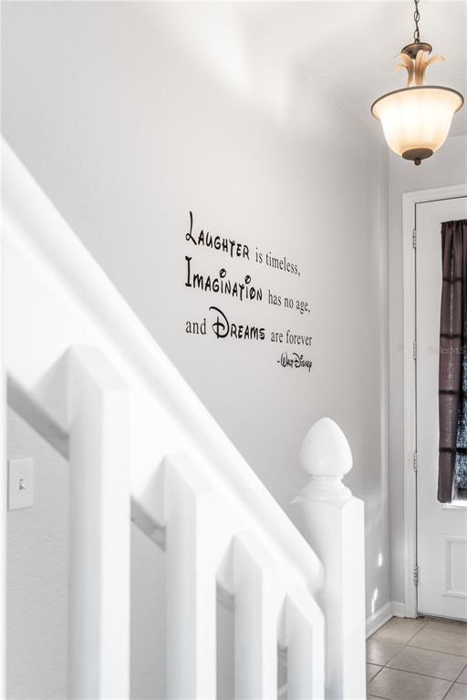 A white staircase railing leads to a wall featuring a Walt Disney quote decal — 7677 FITZCLARENCE STREET, KISSIMMEE, FL