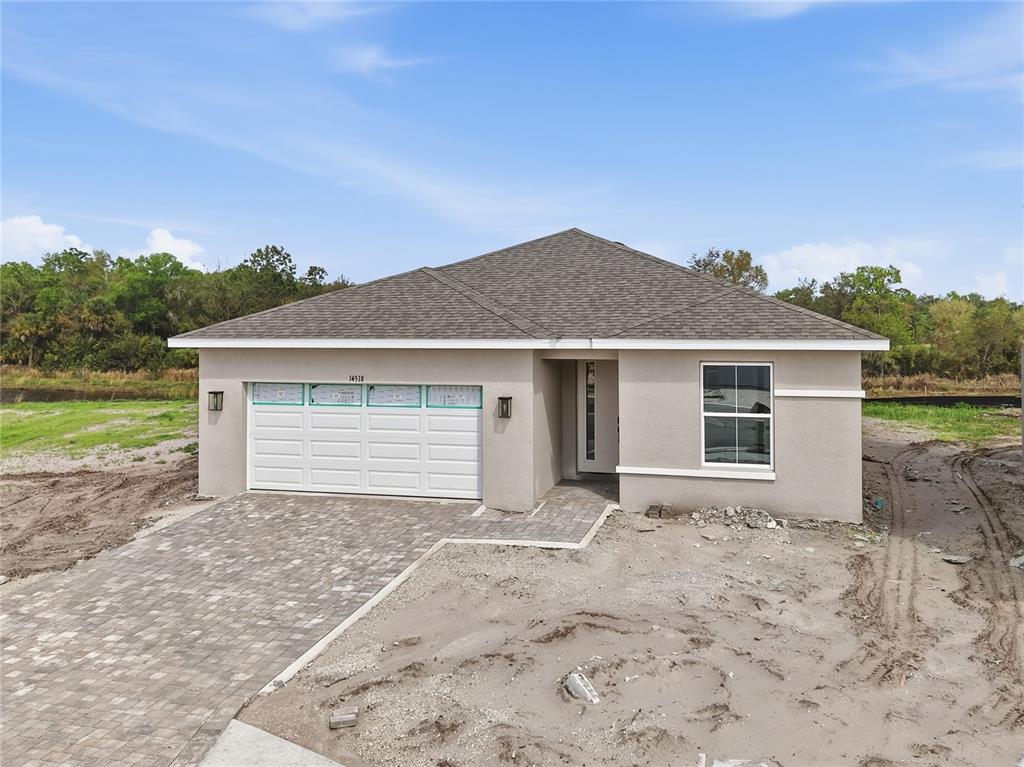 A newly constructed single-story house with a beige stucco exterior and a paved driveway — 14518 BANKS COURT, PARRISH, FL