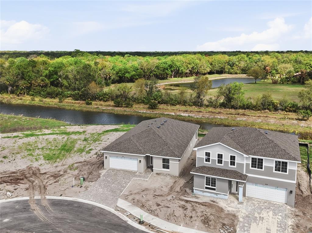 An aerial view shows two newly constructed houses near a canal and wooded area — 14518 BANKS COURT, PARRISH, FL