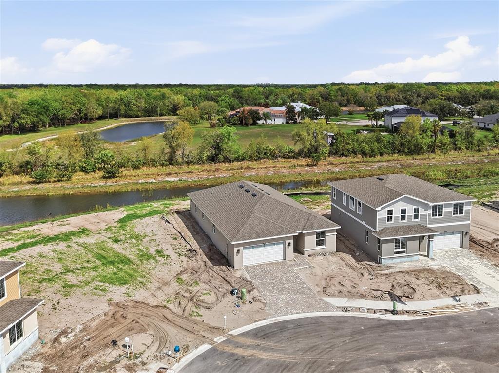 An aerial view shows two newly constructed houses with paved driveways near a small pond — 14518 BANKS COURT, PARRISH, FL