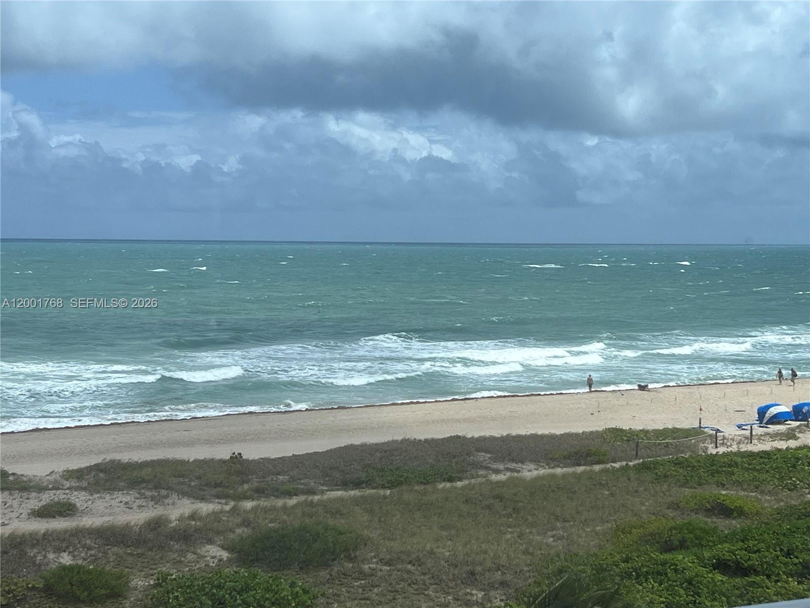A view of a sandy beach and the ocean under a cloudy sky — 710 N Ocean Blvd # 408, Pompano Beach FL 33062, POMPANO BEACH, FL