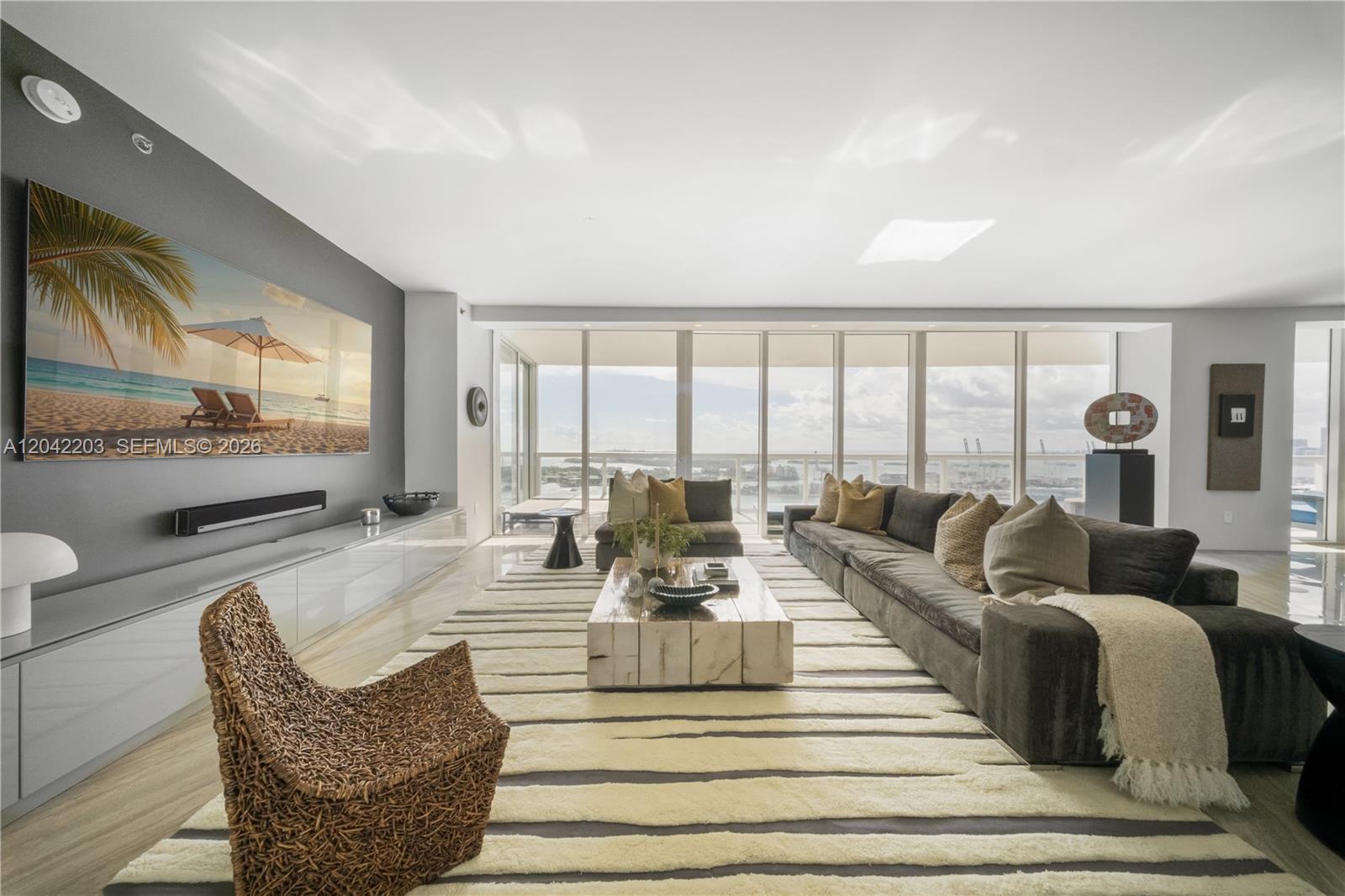 A modern living room features a large sectional sofa, a textured rug, and floor-to-ceiling windows — 450 Alton Rd # 3301, Miami Beach FL 33139, MIAMI BEACH, FL