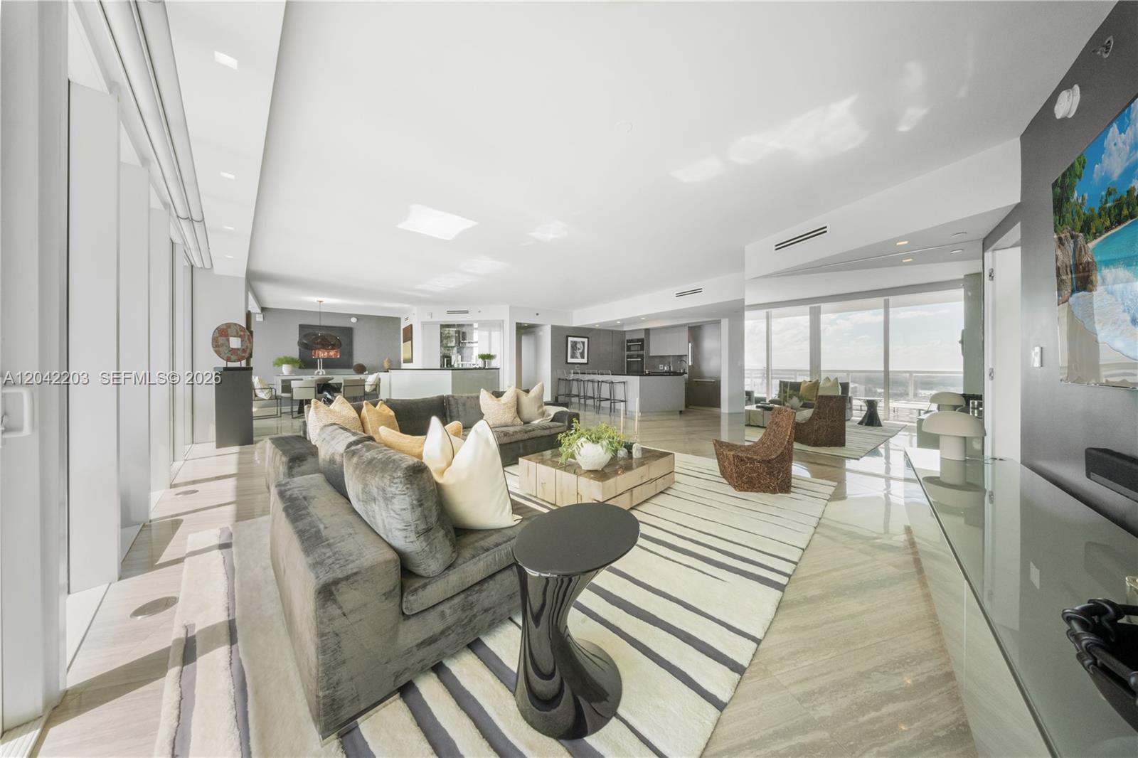A spacious, modern living room features a large gray sectional, striped rug, and open kitchen — 450 Alton Rd # 3301, Miami Beach FL 33139, MIAMI BEACH, FL