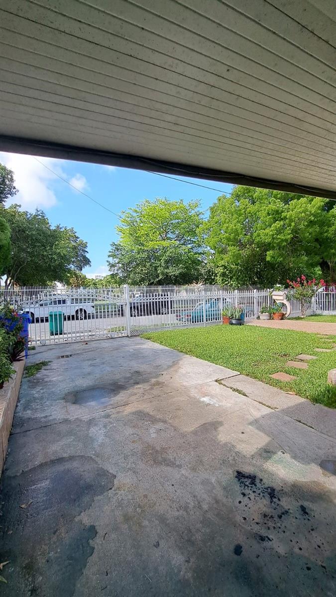 A concrete driveway leads to a gated entrance with a lawn and mature trees — 351 NW 31st St, Miami FL 33127, MIAMI, FL