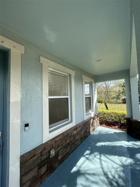 A covered front porch features light blue painted walls, stone veneer siding, and two windows — 3088 SAGITTARIA LANE, ALVA, FL