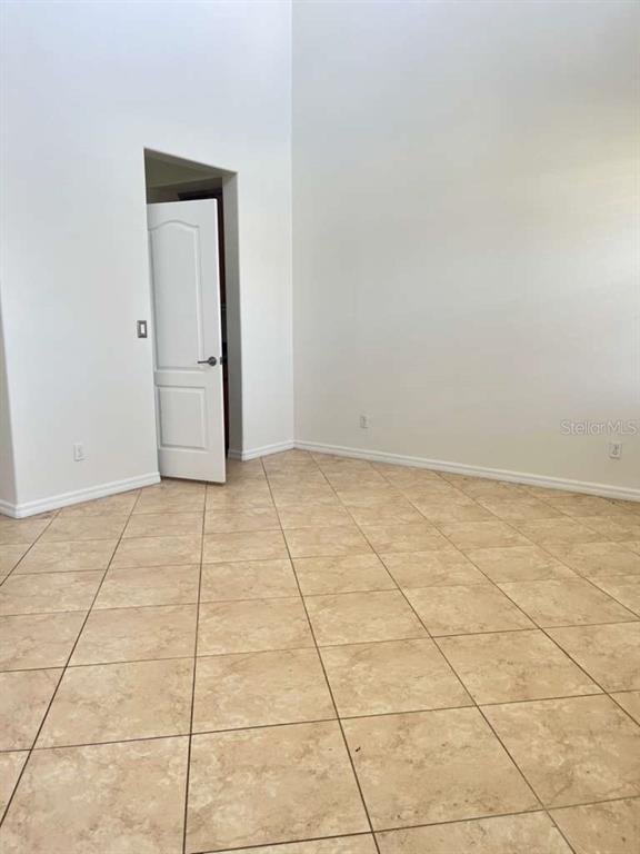 An empty room with high ceilings, white walls, and light-colored square floor tiles — 3088 SAGITTARIA LANE, ALVA, FL