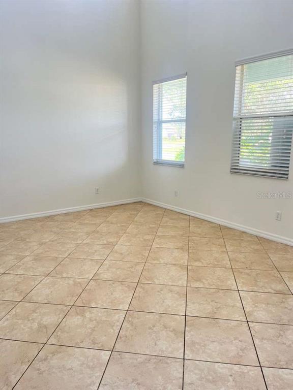 An empty room with beige tile flooring, white walls, and two windows with blinds — 3088 SAGITTARIA LANE, ALVA, FL