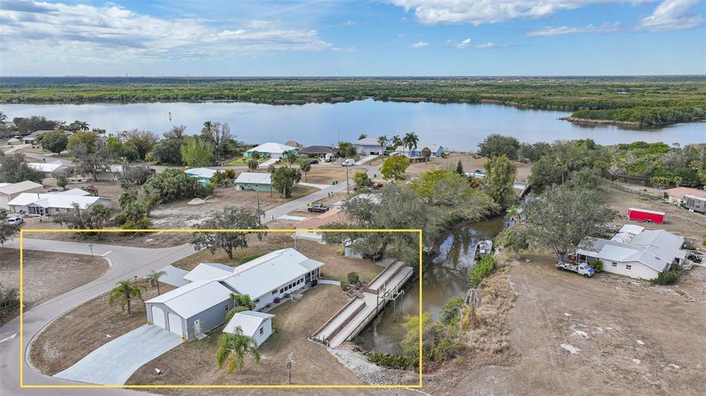 An aerial view shows a house with a metal roof, garage, and private boat ramp — 405 RIDGECREST DRIVE, PUNTA GORDA, FL