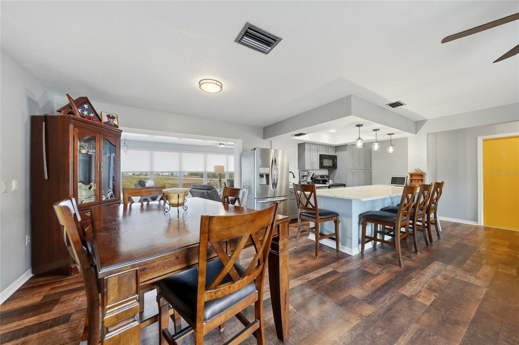 A dining area and kitchen with a large island, wooden furniture, and dark wood flooring — 405 RIDGECREST DRIVE, PUNTA GORDA, FL