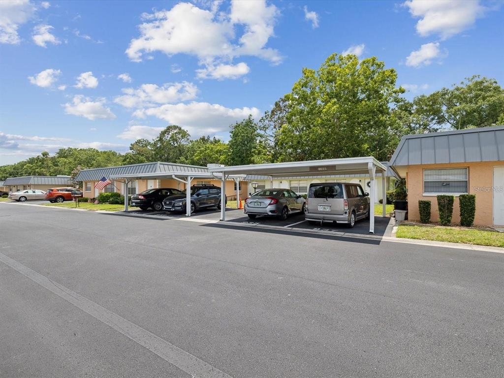 A row of single-story residential buildings features covered parking carports in front of the units — 11935 BAYONET LANE UNIT 0, NEW PORT RICHEY, FL