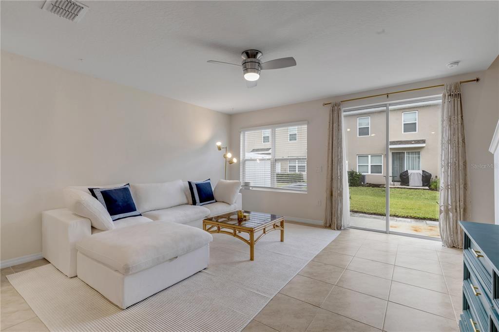 A living room features a white sectional sofa, a glass-topped coffee table, and sliding doors — 60 BELLA OAKS DRIVE, PORT ORANGE, FL