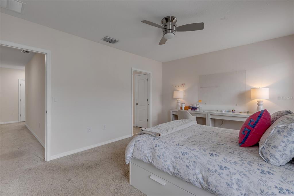 A bedroom features a bed, a desk with a whiteboard, and a ceiling fan — 60 BELLA OAKS DRIVE, PORT ORANGE, FL