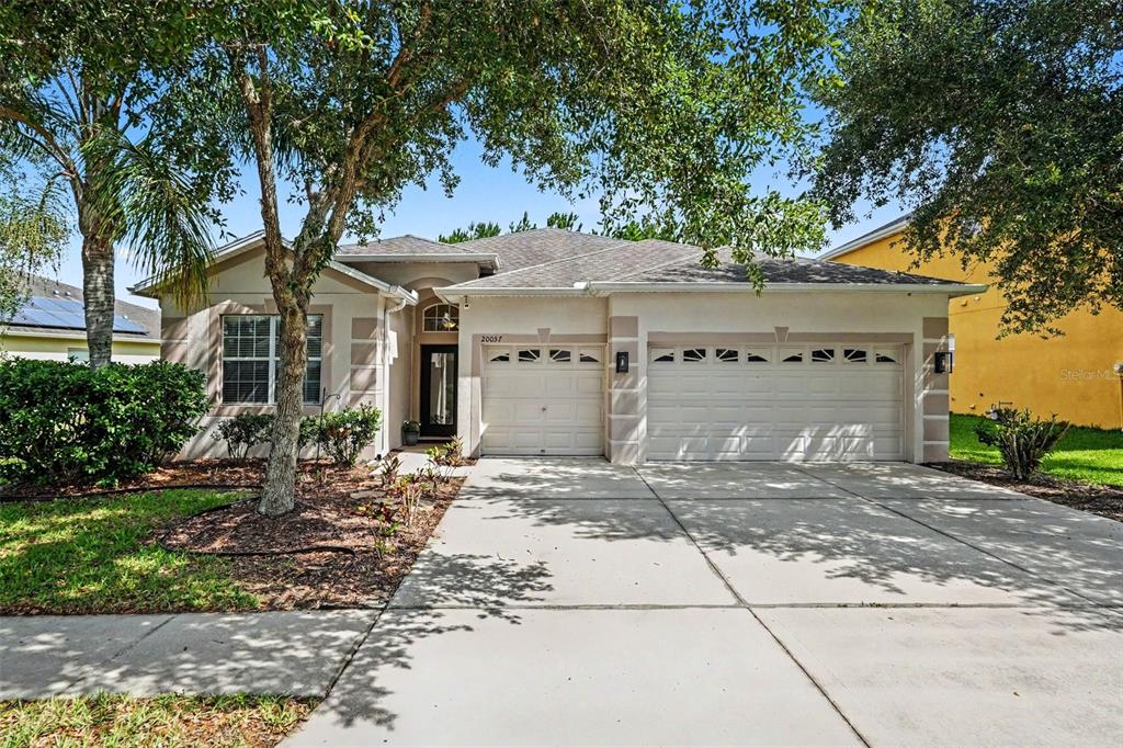 A single-story suburban house with a three-car garage and a concrete driveway — 20057 OAKFLOWER AVENUE, TAMPA, FL