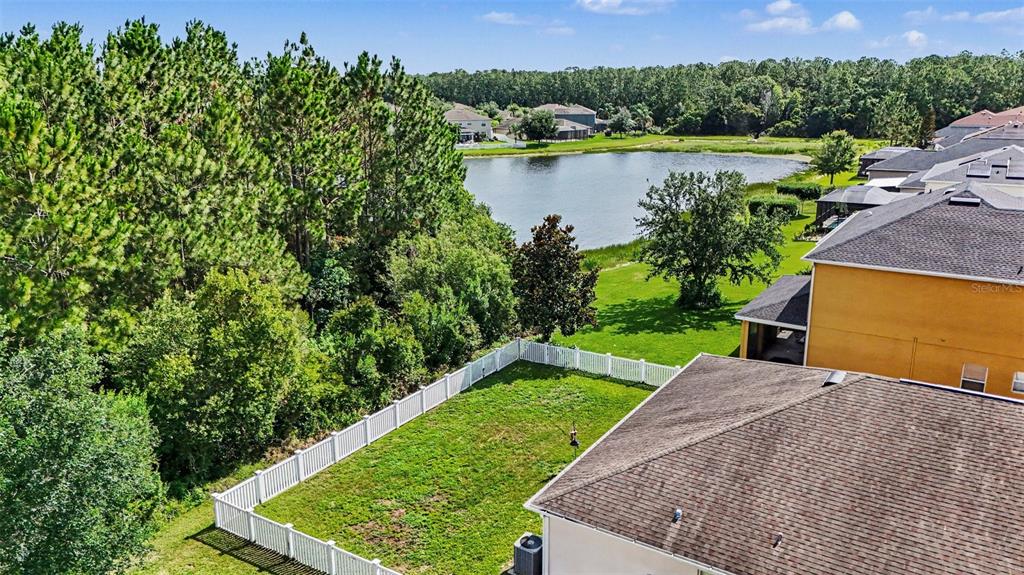 An aerial view shows a fenced backyard, a house, a pond, and surrounding trees — 20057 OAKFLOWER AVENUE, TAMPA, FL